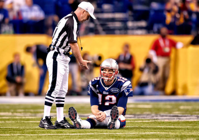 An official offers to help Tom Brady up off the ground during Super Bowl XLVI